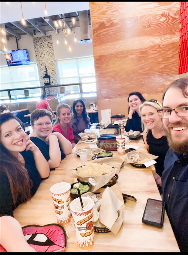 Katie and six other friends eat lunch around a cafeteria table