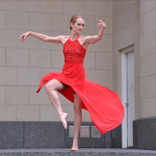 Amy Jennings on stage in a red dress in a dance pose