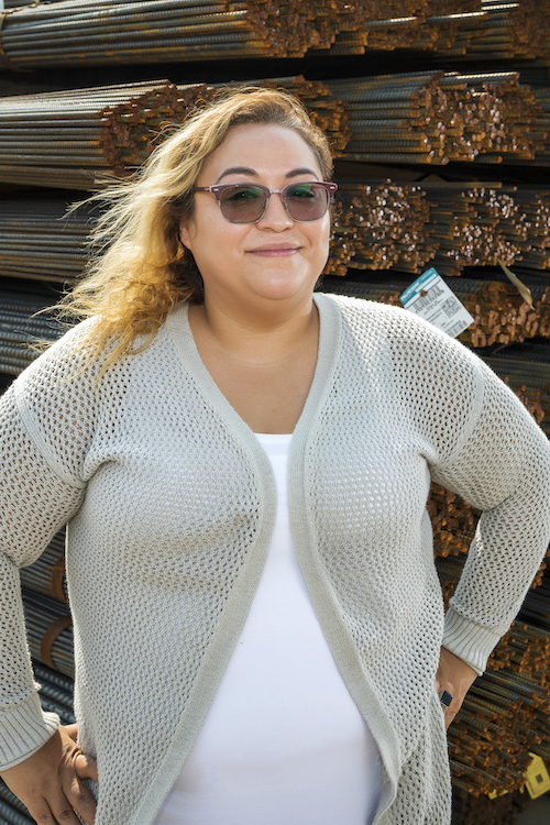 Ana Ambriz standing in front of racks full of steel rebar