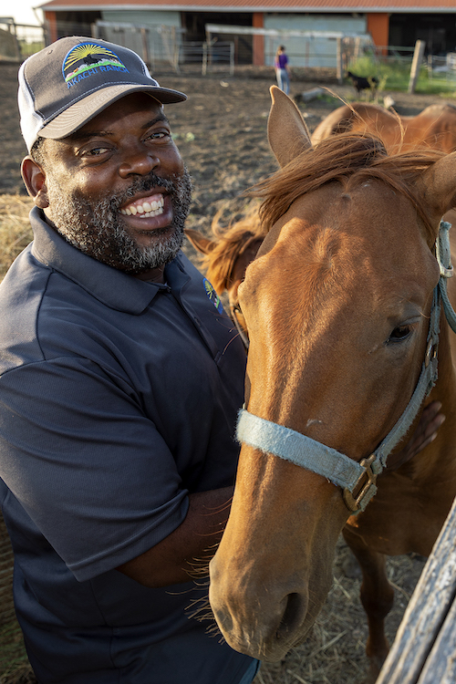 Carlos Walker stands besides a beautiful brown horse