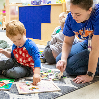 Child and caregiver putting a puzzle together