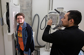 Student getting scanned with an x ray machine by another student