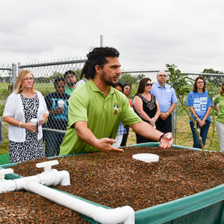 man in green shirt speaking with group of people about sustainability