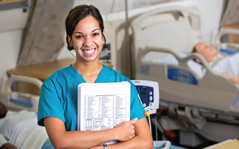 A female nursing student smiles while holding a chart