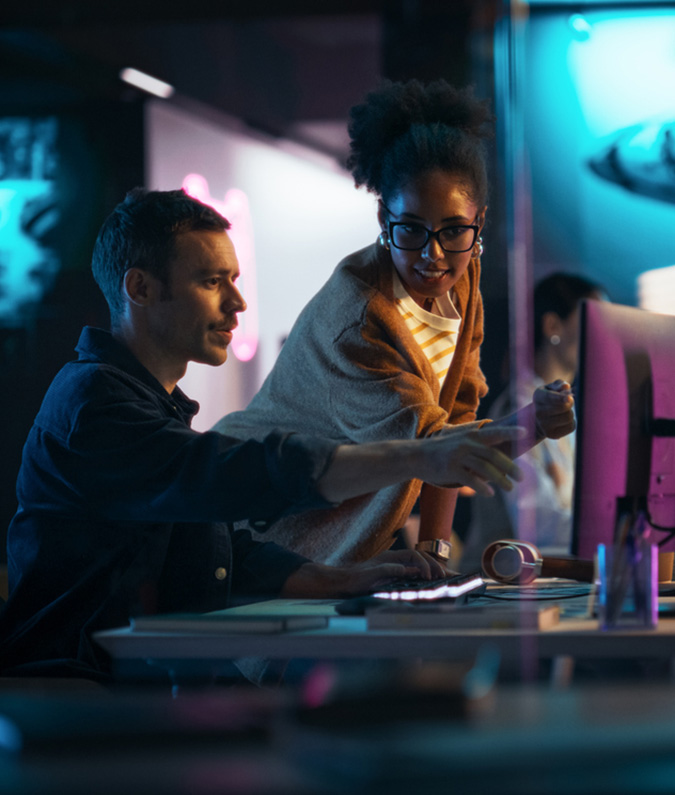 A woman and a man look at a computer monitor together at a desk, exploring options for transferable credit